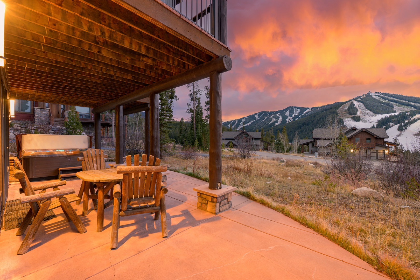 Mountain ski resort property featuring covered patio with hot tub and seating area during stunning sunset.