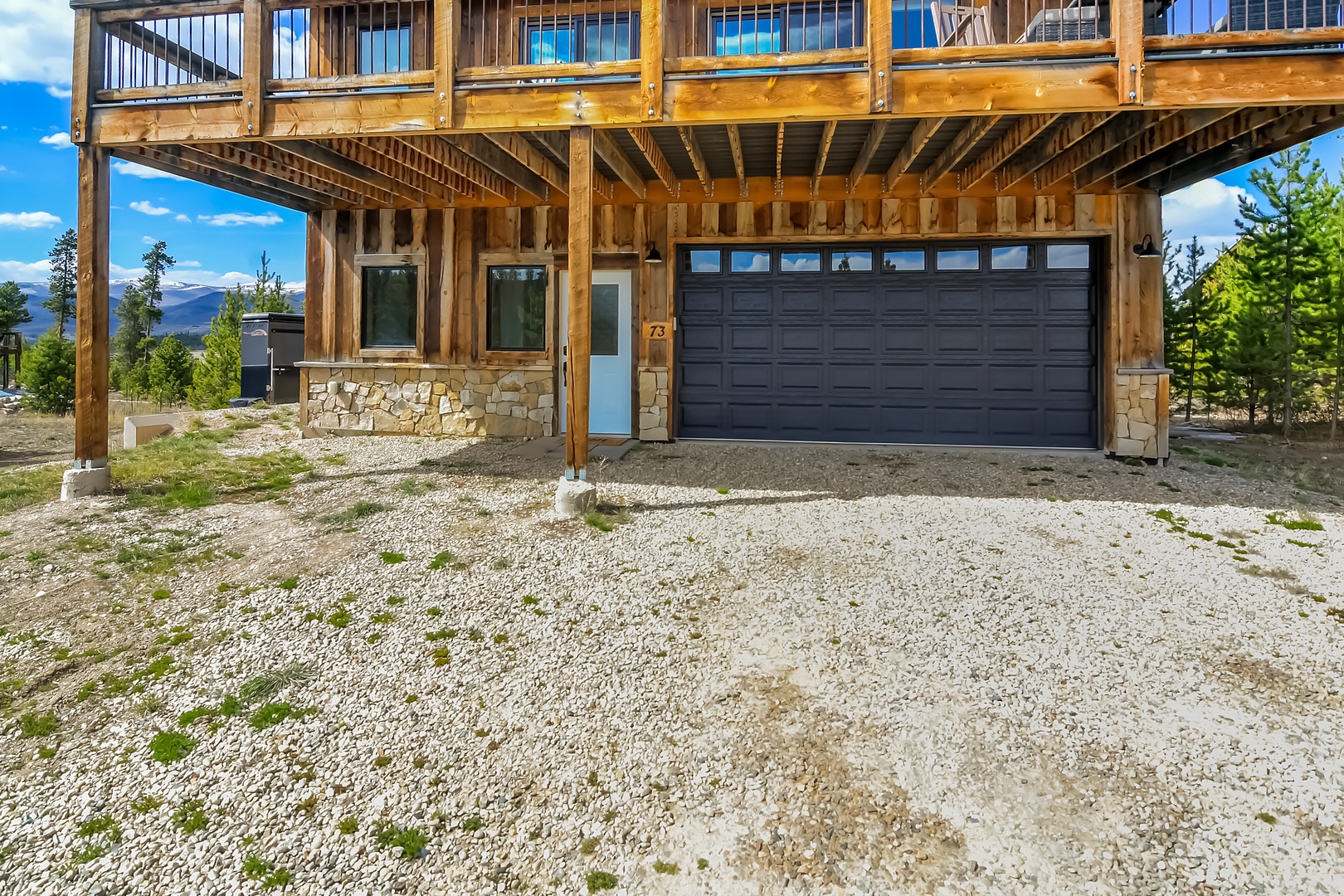 Modern mountain retreat with stone and timber construction, featuring convenient garage parking and scenic natural surroundings.