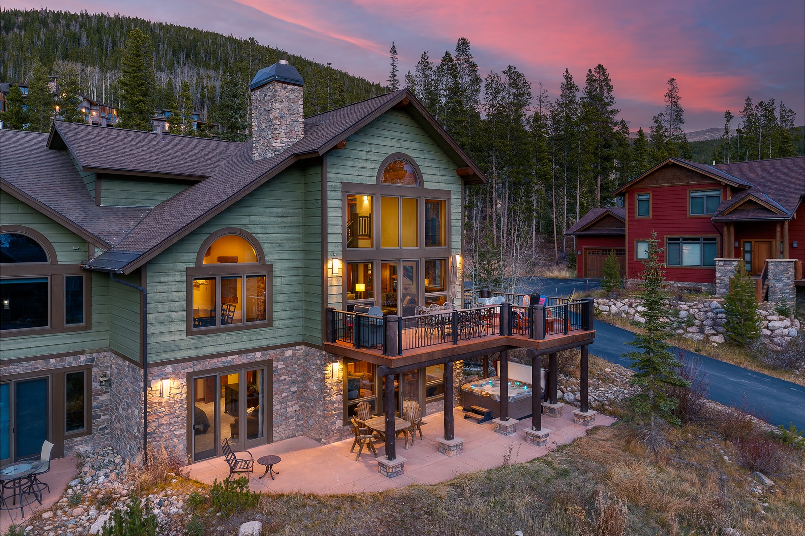 Stunning mountain lodge nestled in a peaceful forest setting with dramatic sunset skies overhead.