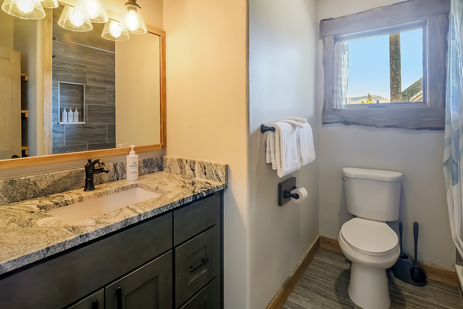 Your private bathroom features granite counters, fresh towels, and natural light through the window.