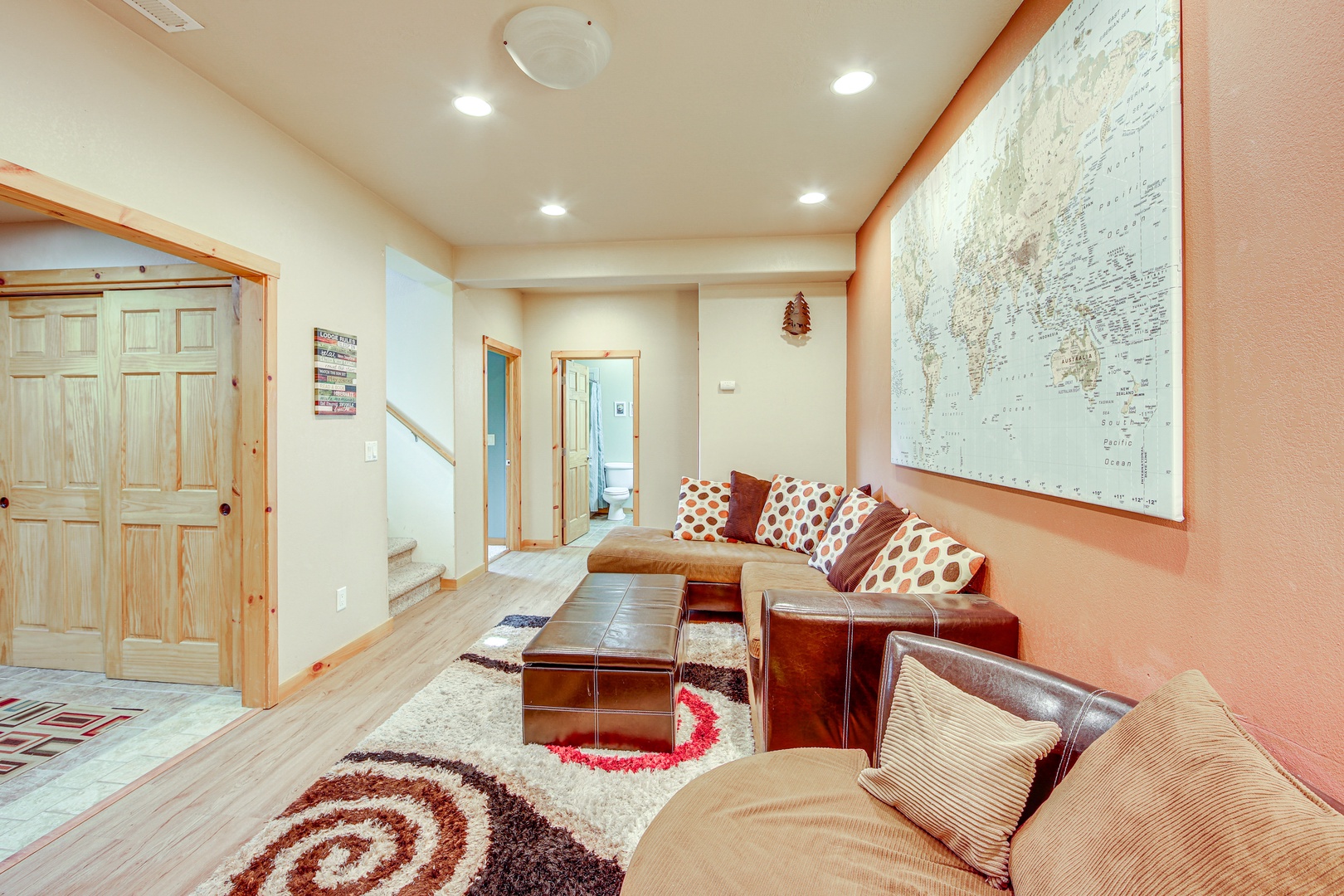Unwind in your spacious living room with comfortable seating, warm earth tones, and inspiring world map wall art.
