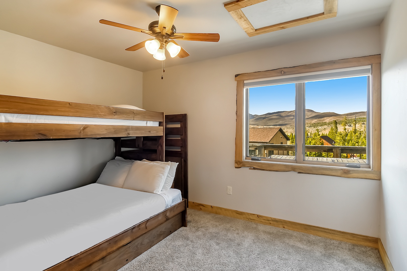 Your cozy bedroom features rustic wooden bunk beds with crisp linens, while mountain vistas stretch beyond your window.