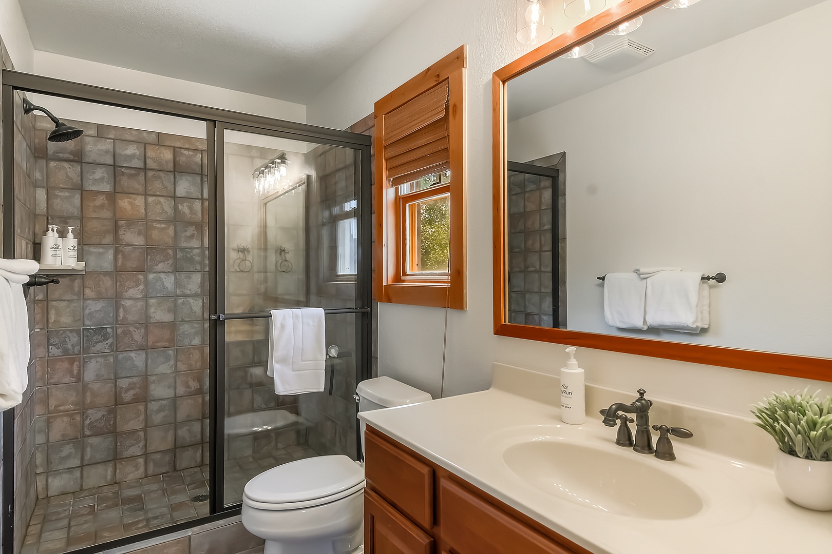 Step into your bathroom with a spacious walk-in shower, fresh towels, and natural light streaming through the window. The warm wood accents and modern fixtures create your perfect retreat after a day of adventure.