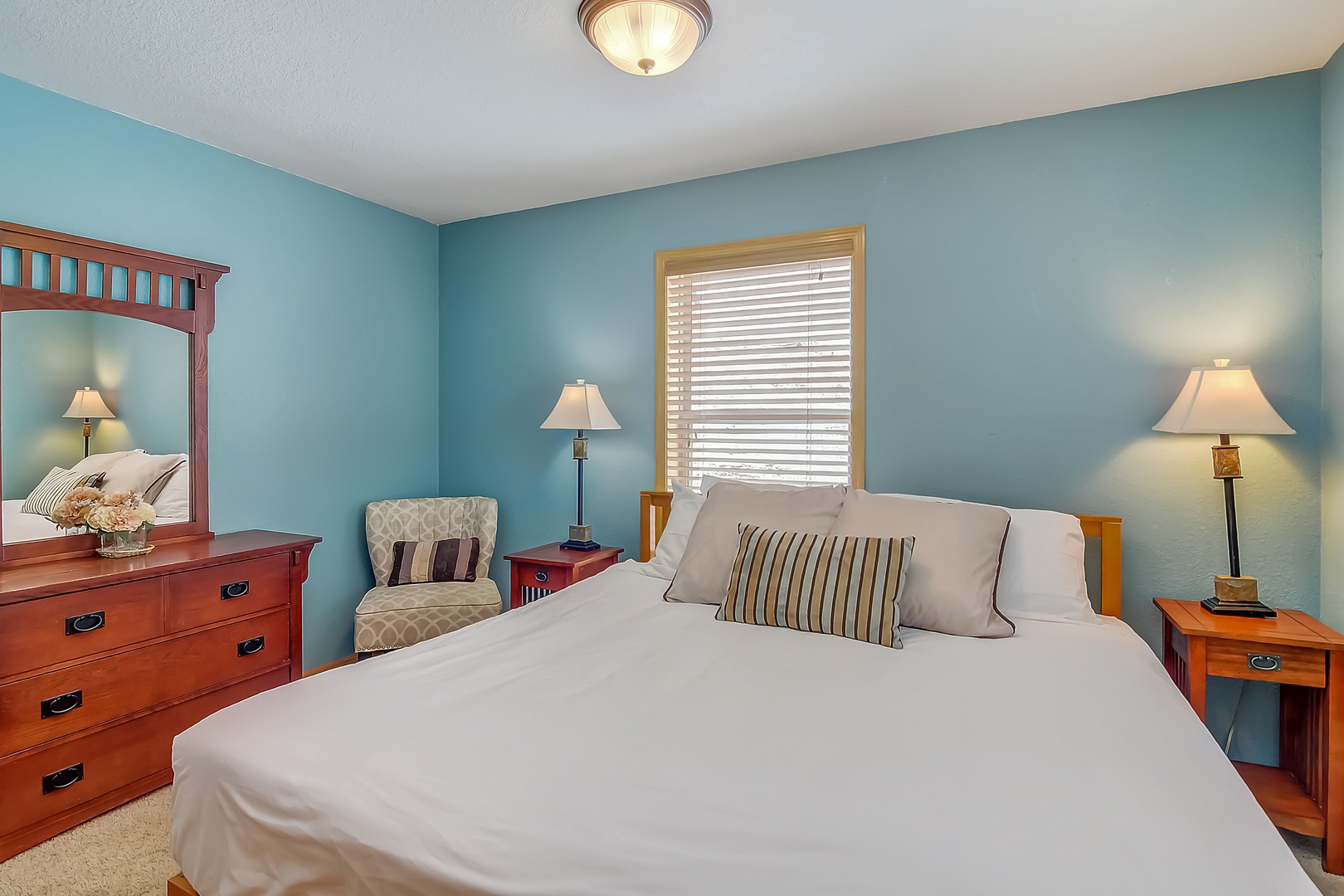 Unwind in your tranquil bedroom featuring calming turquoise walls, crisp linens, and warm wood furnishings that create the perfect retreat.