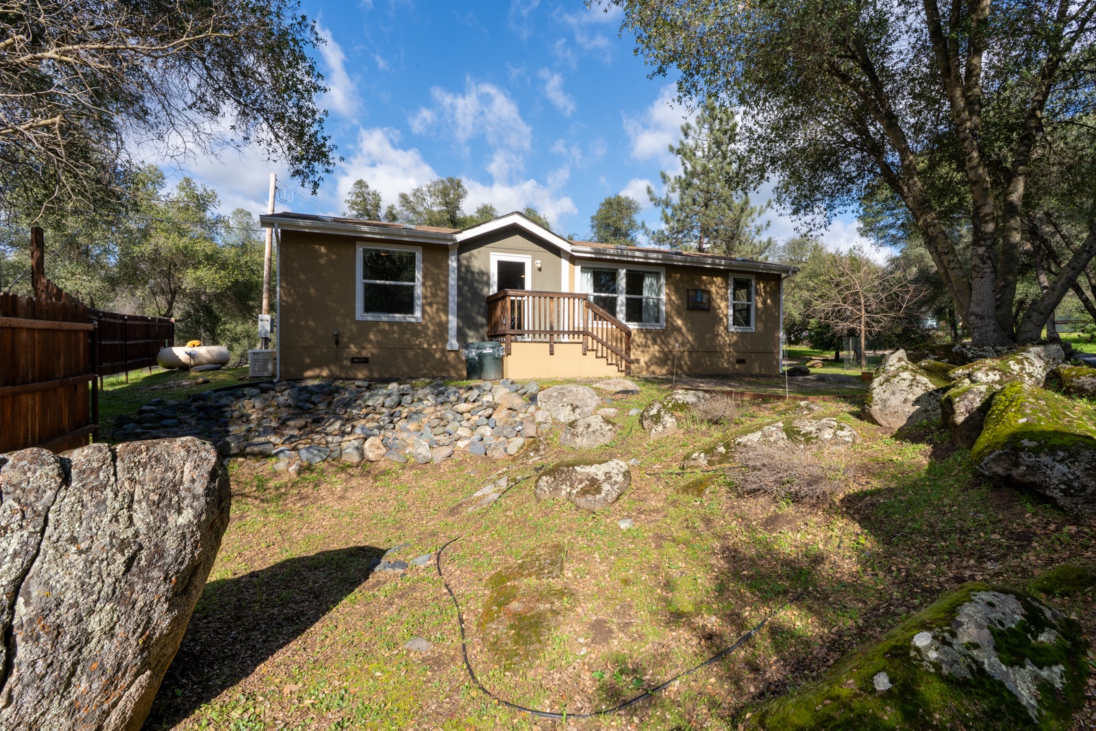 A charming home nestled among mature trees and natural rock formations, offering a peaceful retreat with scenic outdoor spaces.
