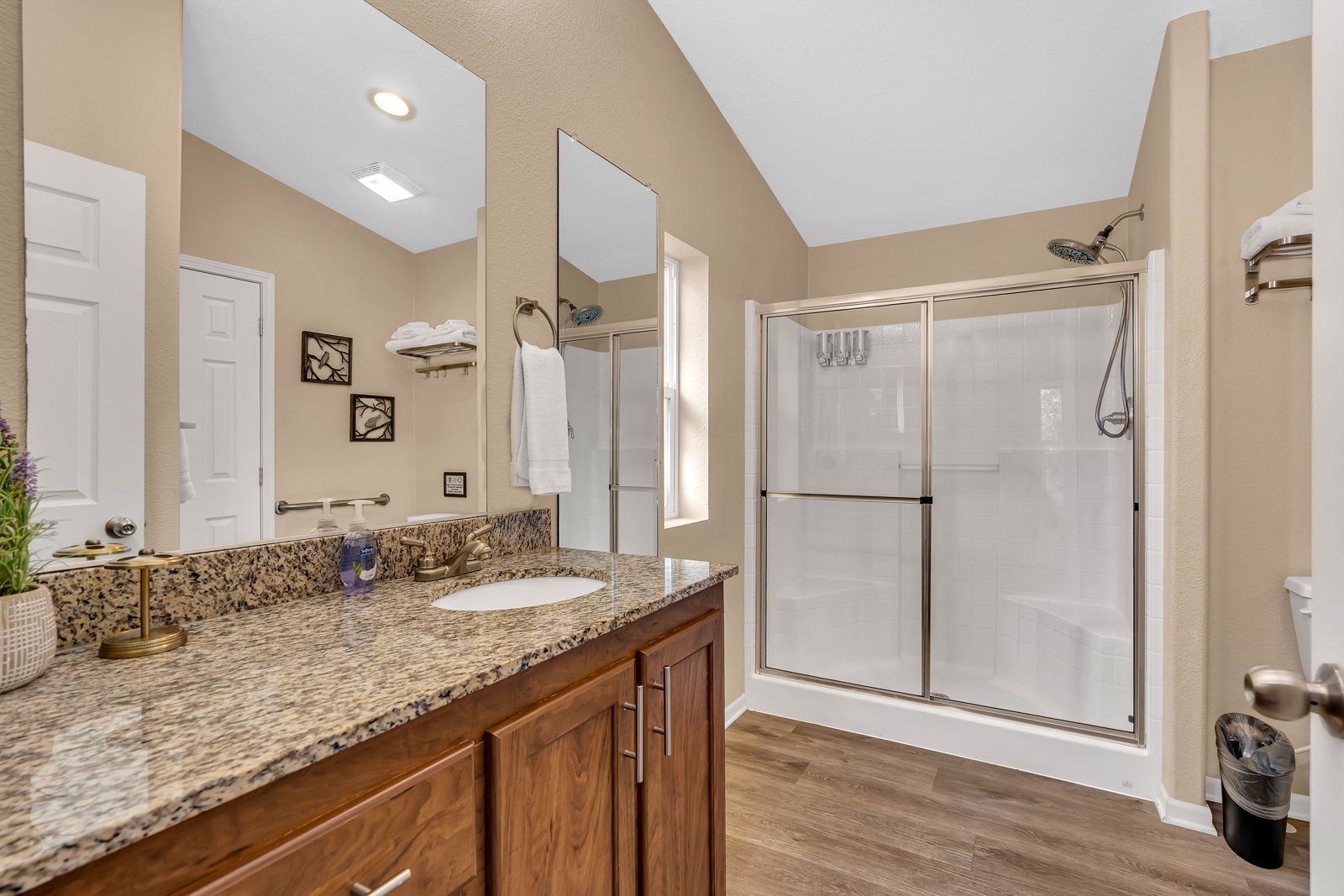 Refresh in your spacious bathroom featuring a glass shower, and warm wood finishes.