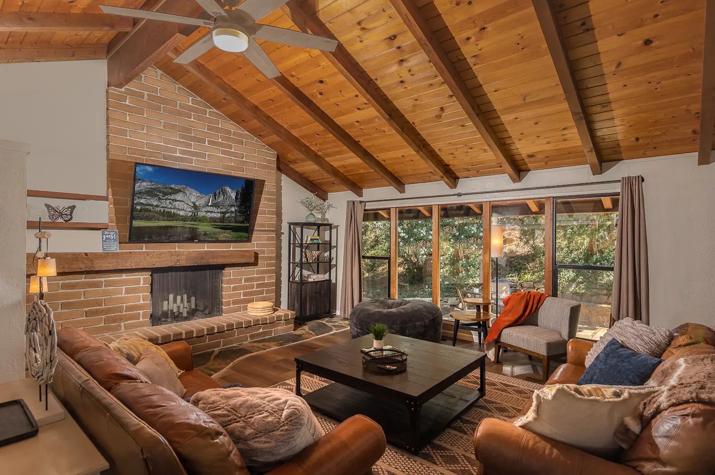 Cozy up by your crackling fireplace under soaring wooden beams, where leather seating and mountain views create the perfect retreat atmosphere.