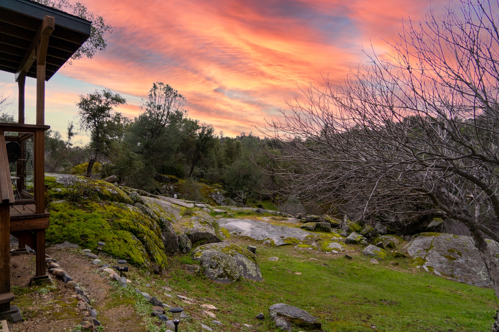 Dramatic sunset paints the sky in vibrant orange and pink hues above the property's natural landscape.