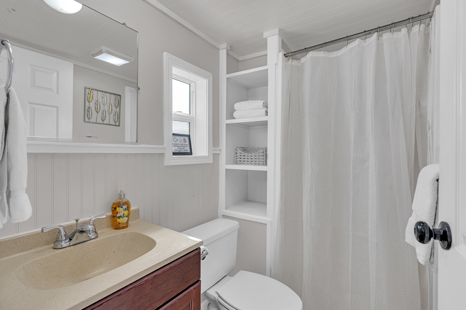 Step into your bright, clean bathroom and thoughtful built-in storage shelves perfectly stocked with fresh towels and essentials for your comfort.