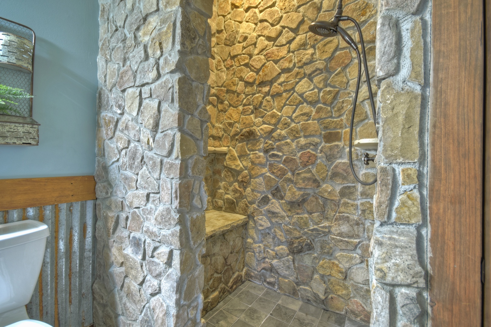 River Lodge- Lower level stone bathroom shower with a bench