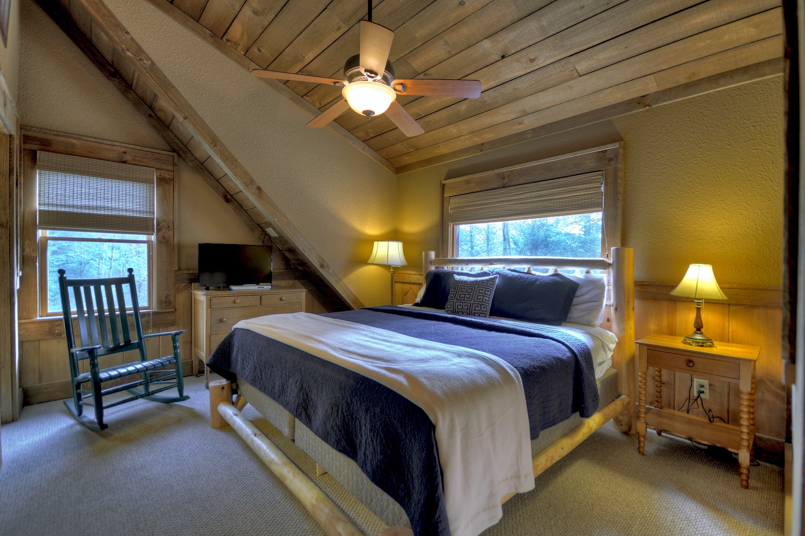 Reel Creek Lodge- Upper level king bedroom with a rocking chair and TV