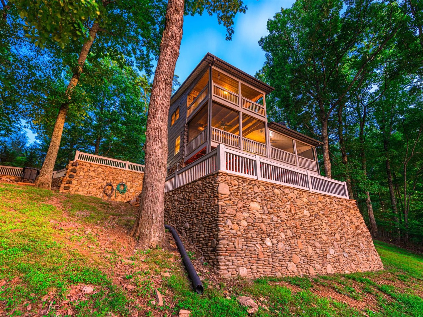 Aska Bliss- Front facing view of the cabin and the stone wall holding the firepit