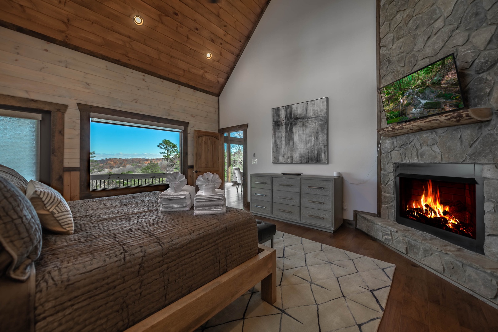The Ridgeline Retreat- Main level king master suite with a fireplace and TV