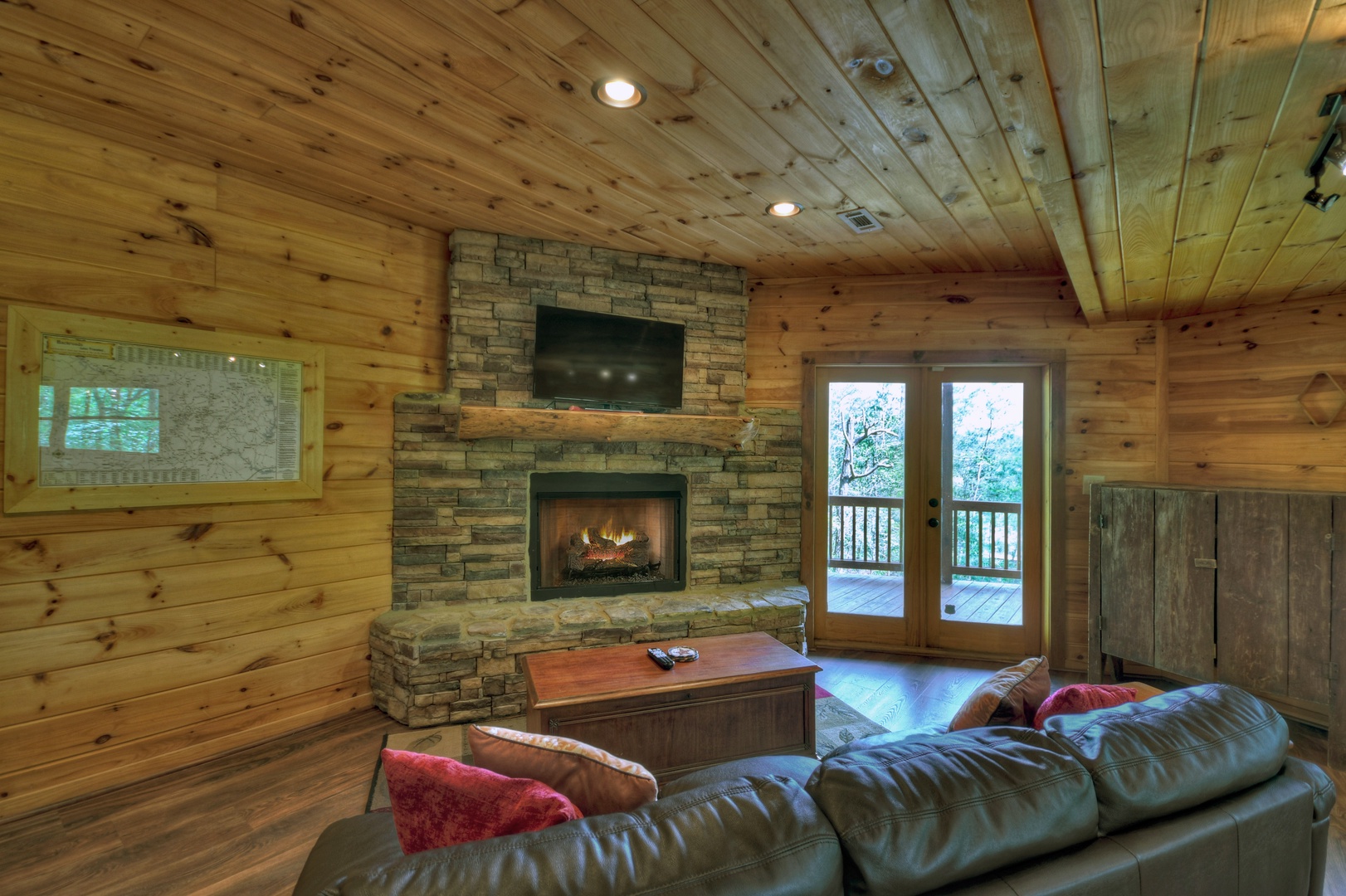 Aska Lodge- Lower level common area with seating, a fireplace and a TV with deck access