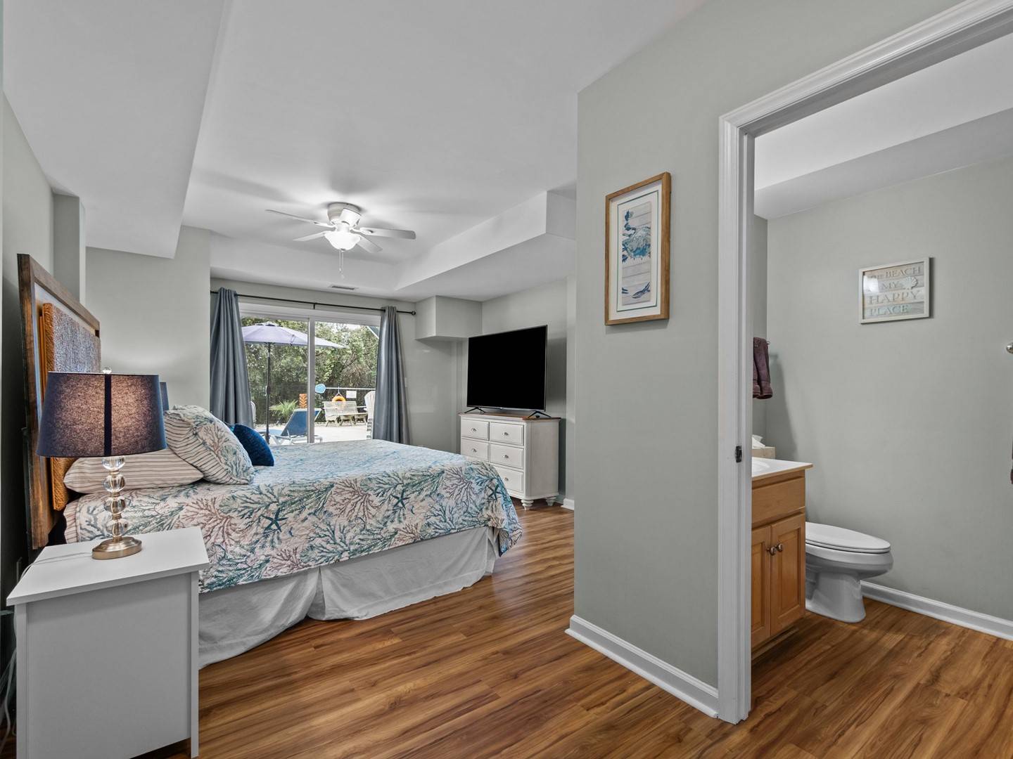 Your spacious bedroom features warm hardwood floors, ceiling fan comfort, and patio access with garden views for peaceful mornings.
