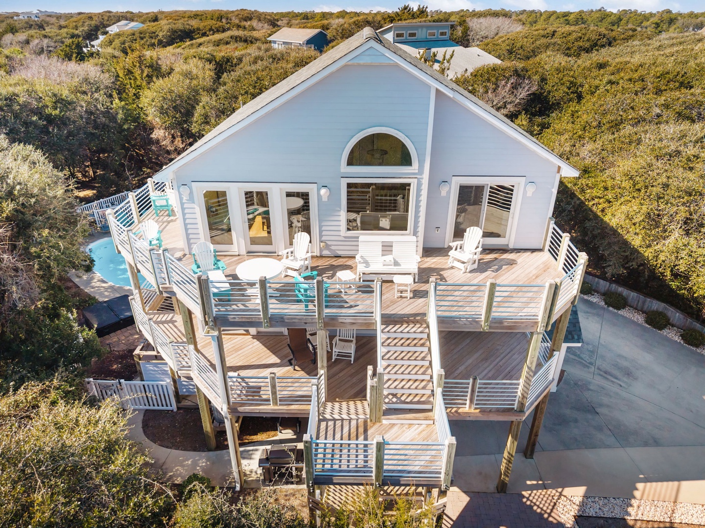 Elevated beach house with expansive decks nestled among coastal vegetation, featuring multiple levels of outdoor living space.