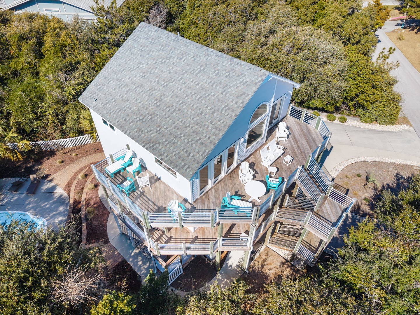 Elevated coastal home features multiple deck levels with turquoise outdoor seating and natural surroundings.
