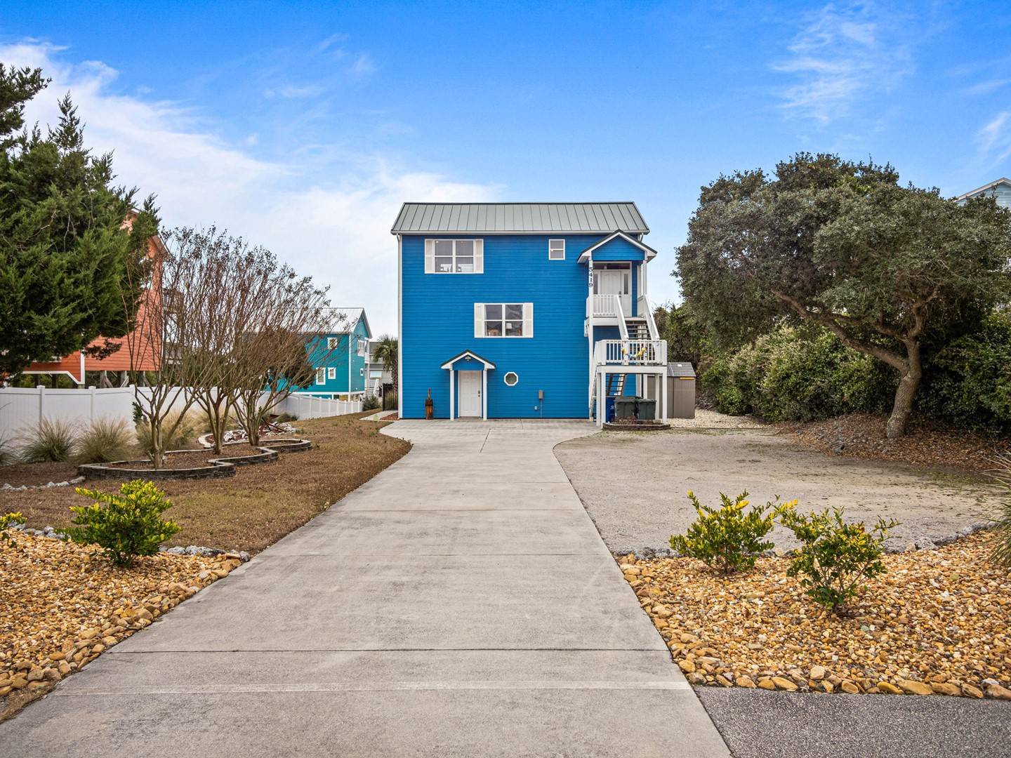 Charming blue beach house with coastal landscaping and easy parking access in a peaceful neighborhood setting.