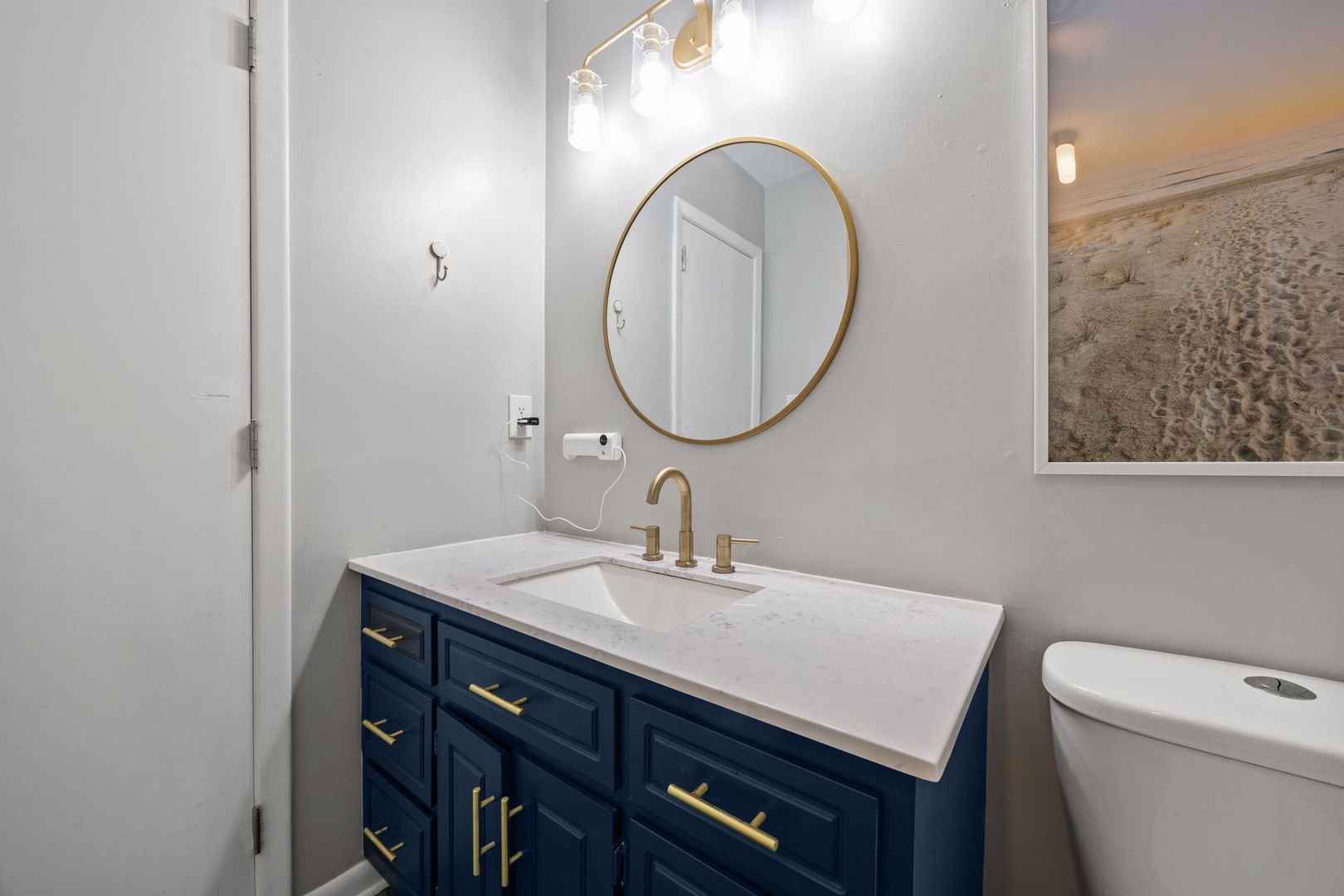 Refresh in your elegant bathroom with marble countertops, brass fixtures, and crisp coastal artwork.