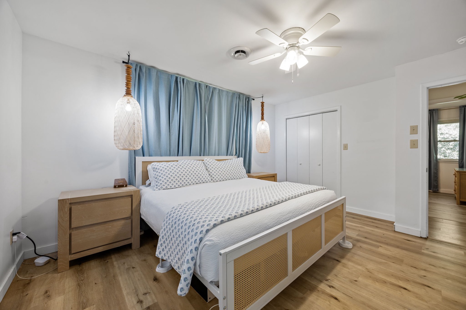 Unwind in your serene coastal-inspired bedroom with crisp linens, gentle ceiling fan breeze, and charming pendant lights.