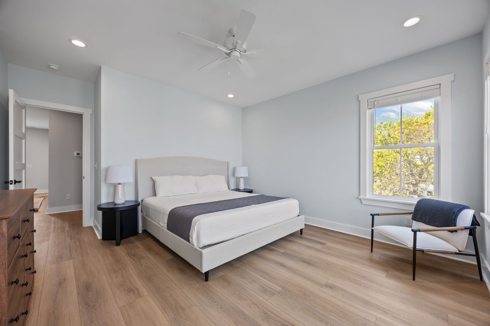 Rest peacefully in your serene bedroom featuring a comfortable bed, modern furnishings, and natural light streaming through large windows.