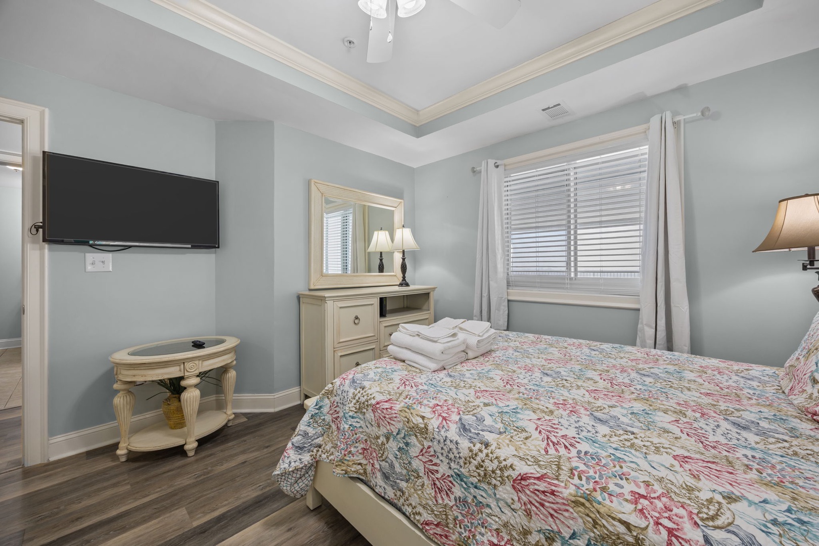 Sink into your comfortable bed in this serene bedroom where soft morning light filters through blinds, creating the perfect atmosphere for restful sleep.