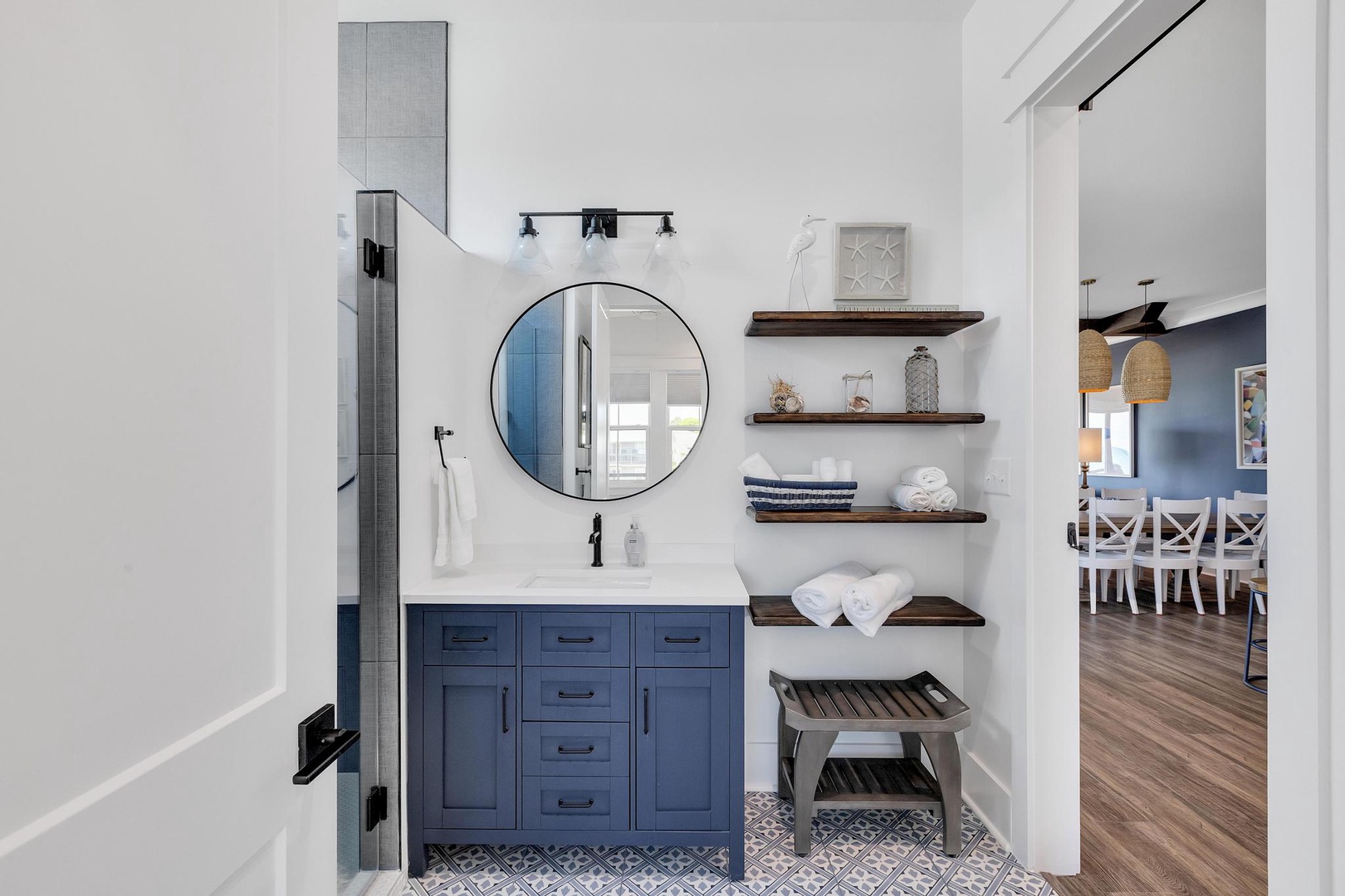 Your stylish bathroom features crisp white subway tile, a spacious vanity with coastal navy cabinetry, and soft towels waiting on open shelving to make you feel right at home.