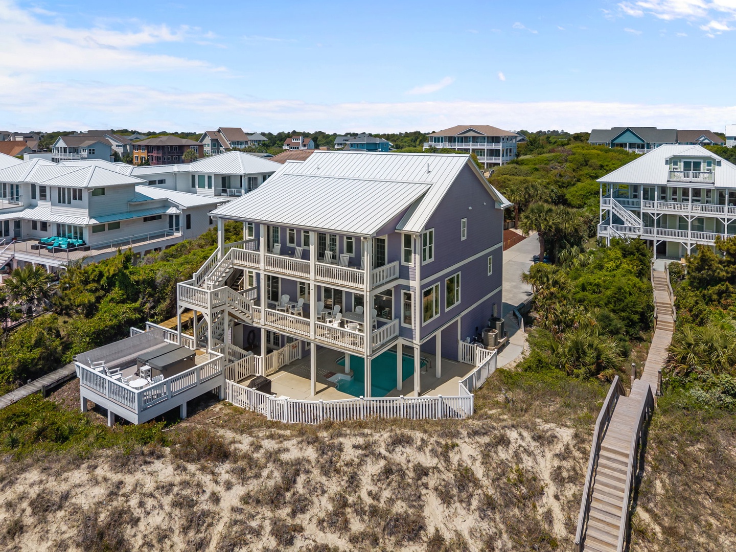 Elevated coastal home with private pool and decking, nestled among lush vegetation with beach boardwalk access.