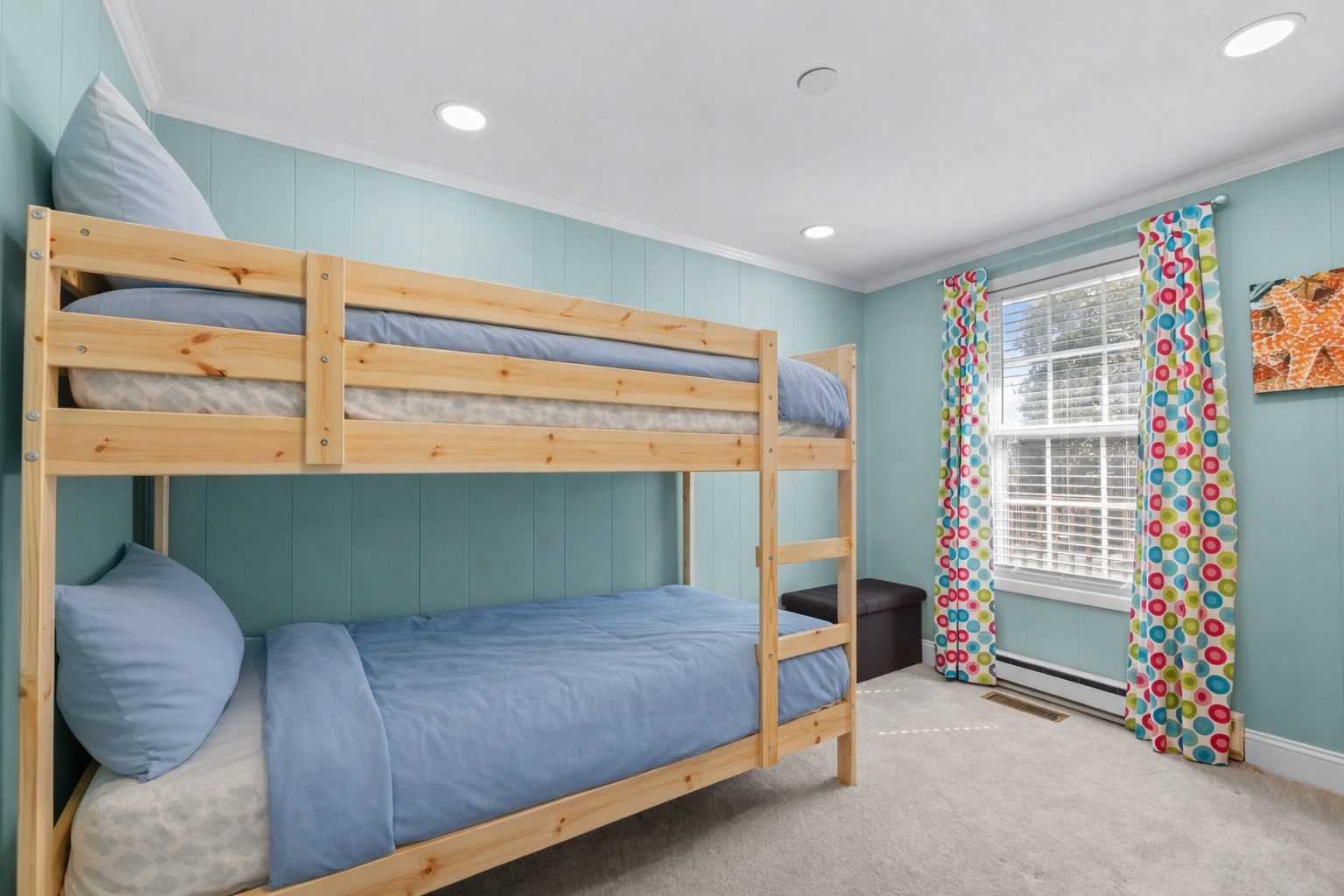 Rest peacefully in your cozy bunk bed bedroom with cheerful blue walls and bright colorful curtains creating the perfect family-friendly retreat.