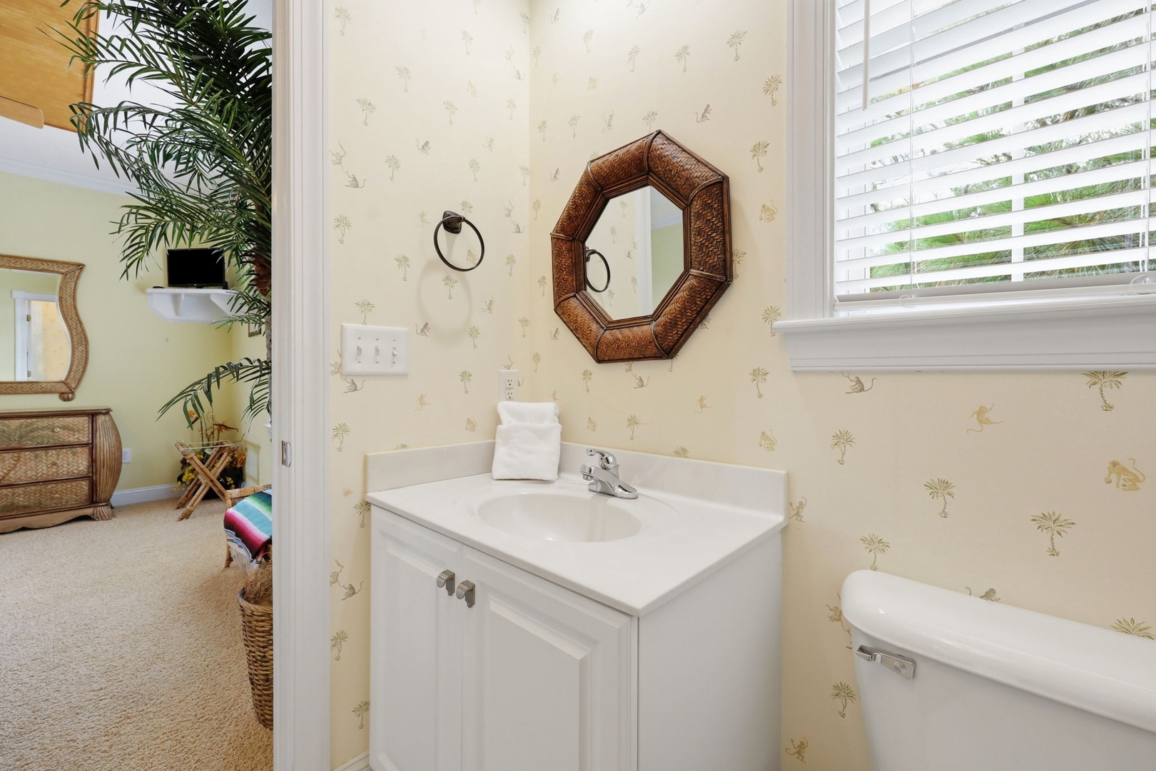Freshen up in your private bathroom featuring charming coastal wallpaper, a clean vanity, and fluffy towels. Natural light adds warmth and a welcoming touch to your daily routine.