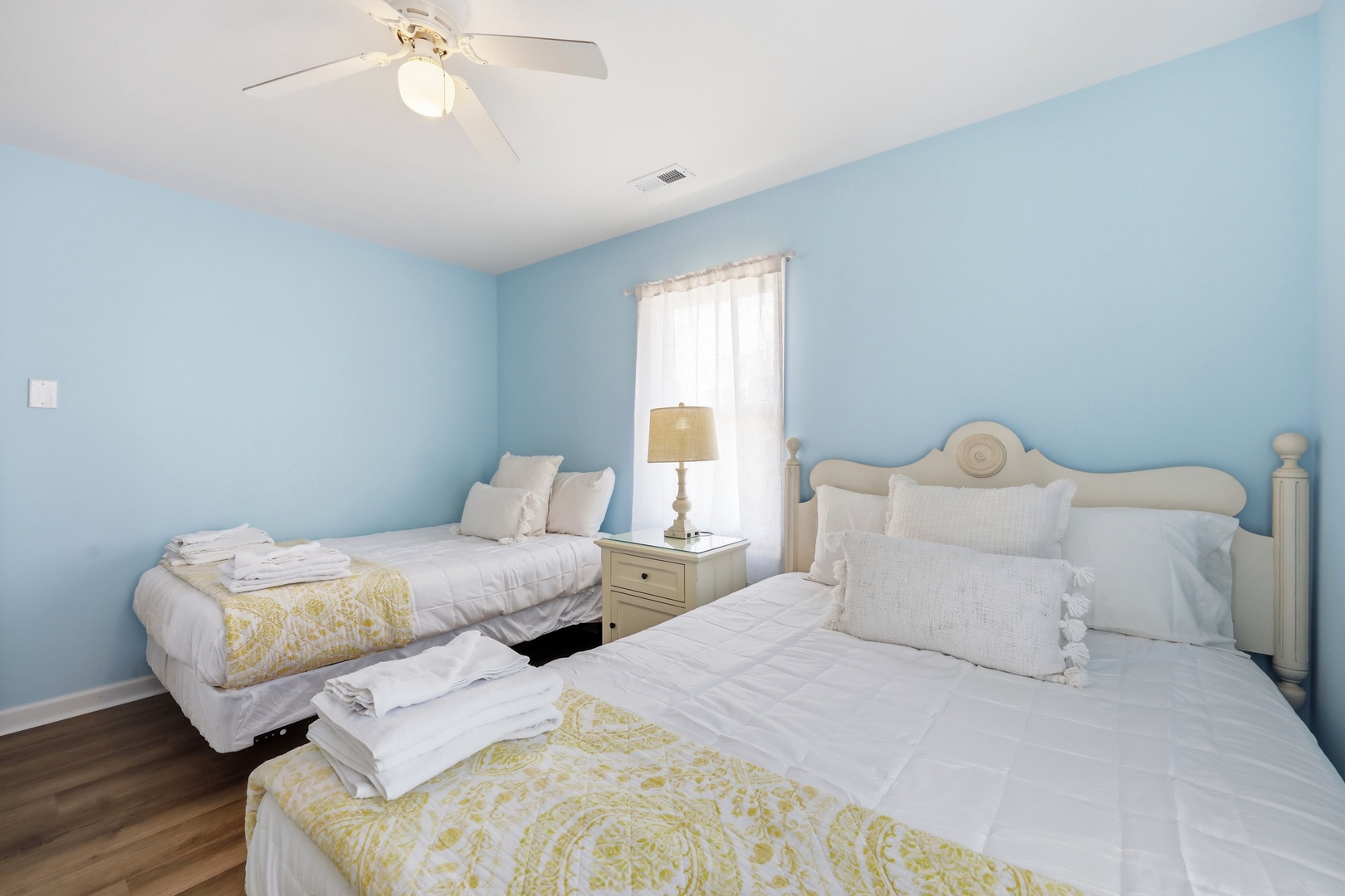 Rest easy in this serene coastal bedroom with plush beds dressed in crisp linens and soft throws, where gentle sea breezes and natural light welcome you home.