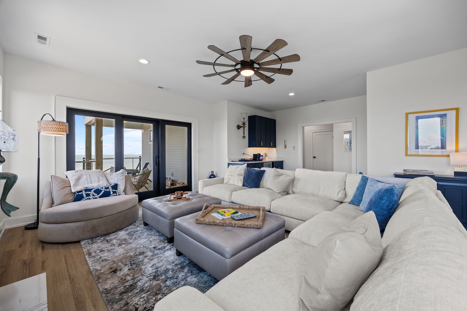 Your spacious living room features a plush sectional sofa perfect for gathering, with ocean views through sliding glass doors.
