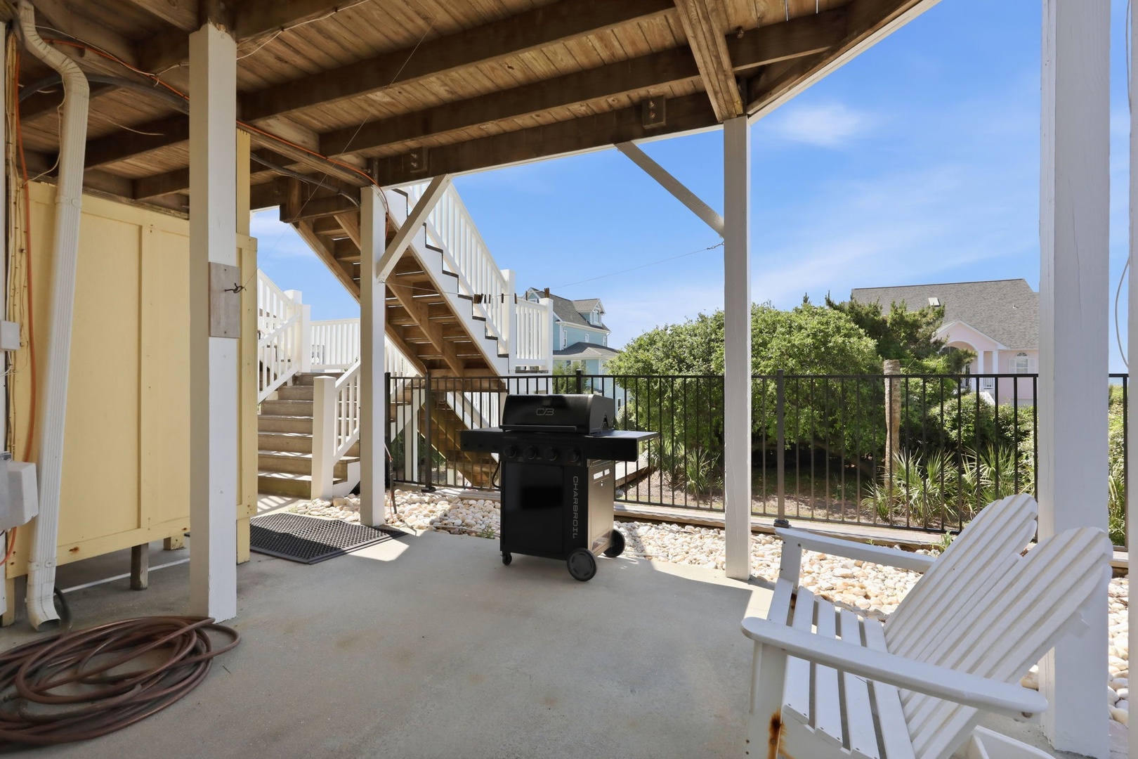 Your private covered patio features a BBQ grill and lounge seating where you can relax, surrounded by coastal greenery and blue sky.