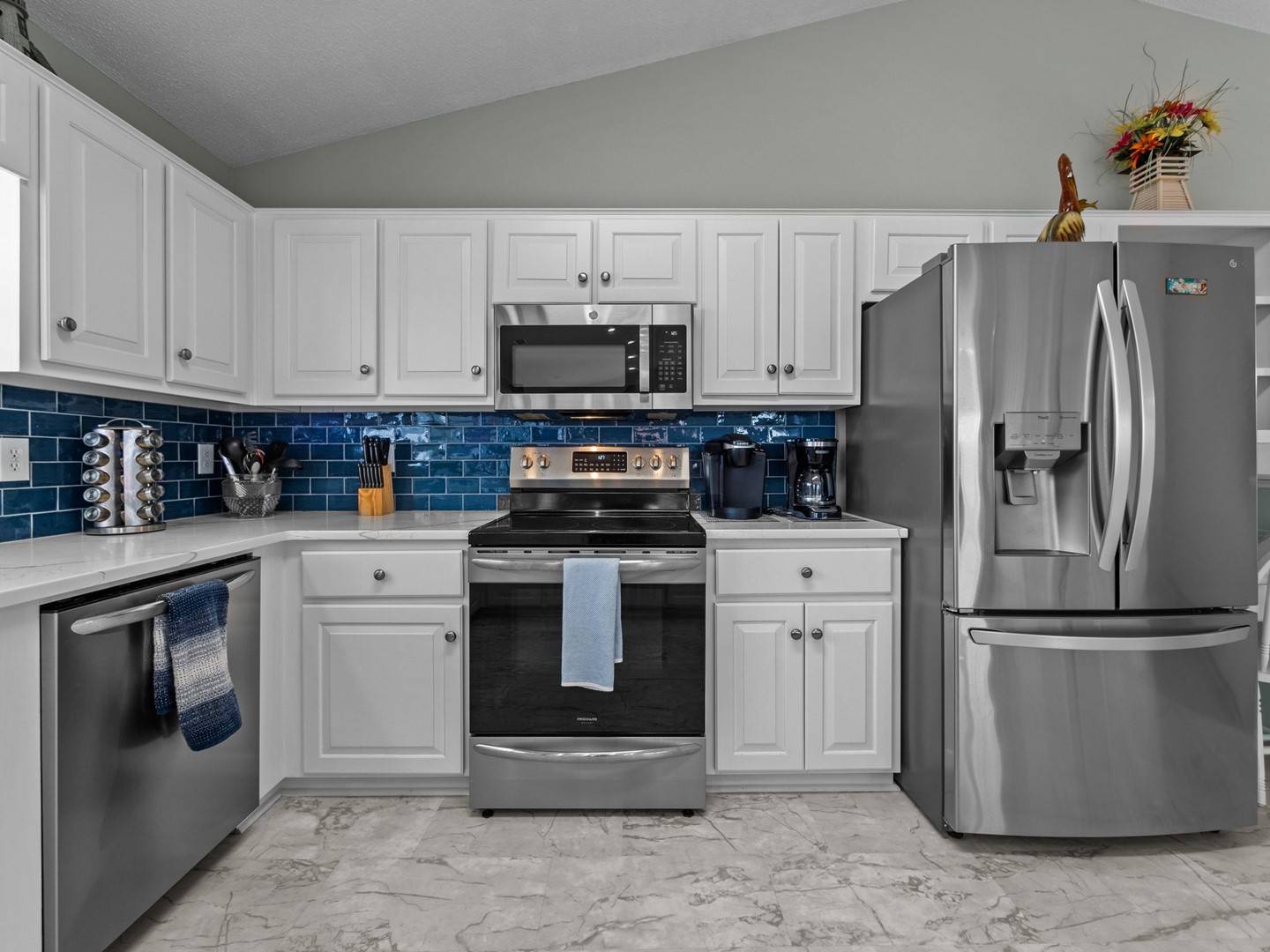 Your fully equipped kitchen features crisp white cabinetry, stunning blue tile backsplash, and modern stainless steel appliances for effortless home-cooked meals.
