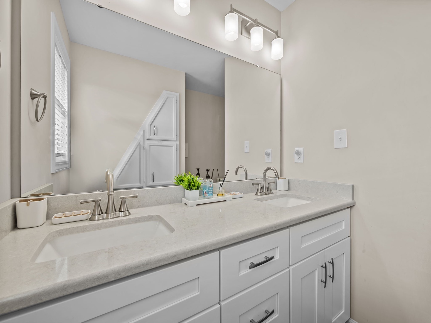 Refresh in your elegant dual-sink bathroom with pristine quartz counters and bright vanity lighting for perfect morning routines.