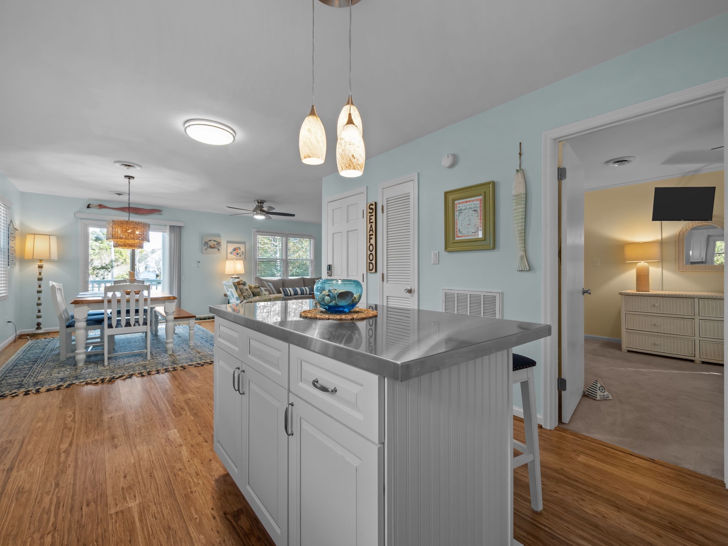 Your bright coastal kitchen flows into a cozy living space where aqua walls and warm wood floors create a beachy haven for cooking and relaxing together.