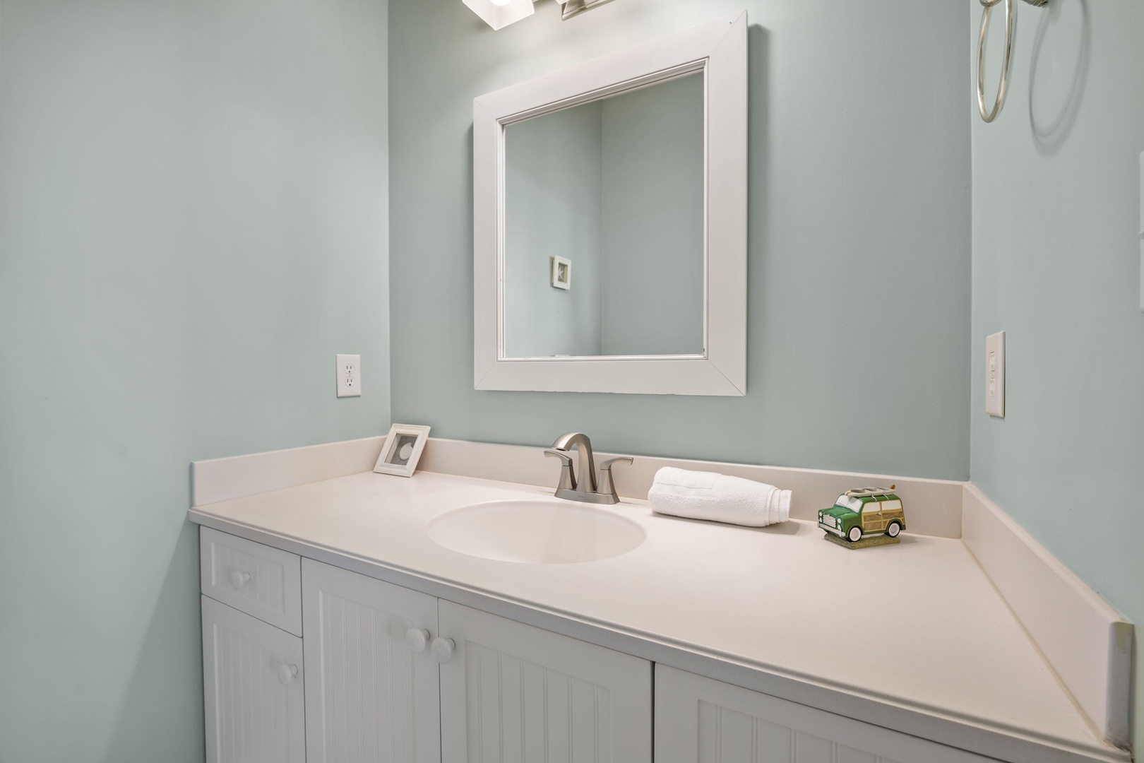 Refresh in your serene bathroom featuring soothing mint walls, crisp white vanity, and thoughtful amenities waiting for your arrival.