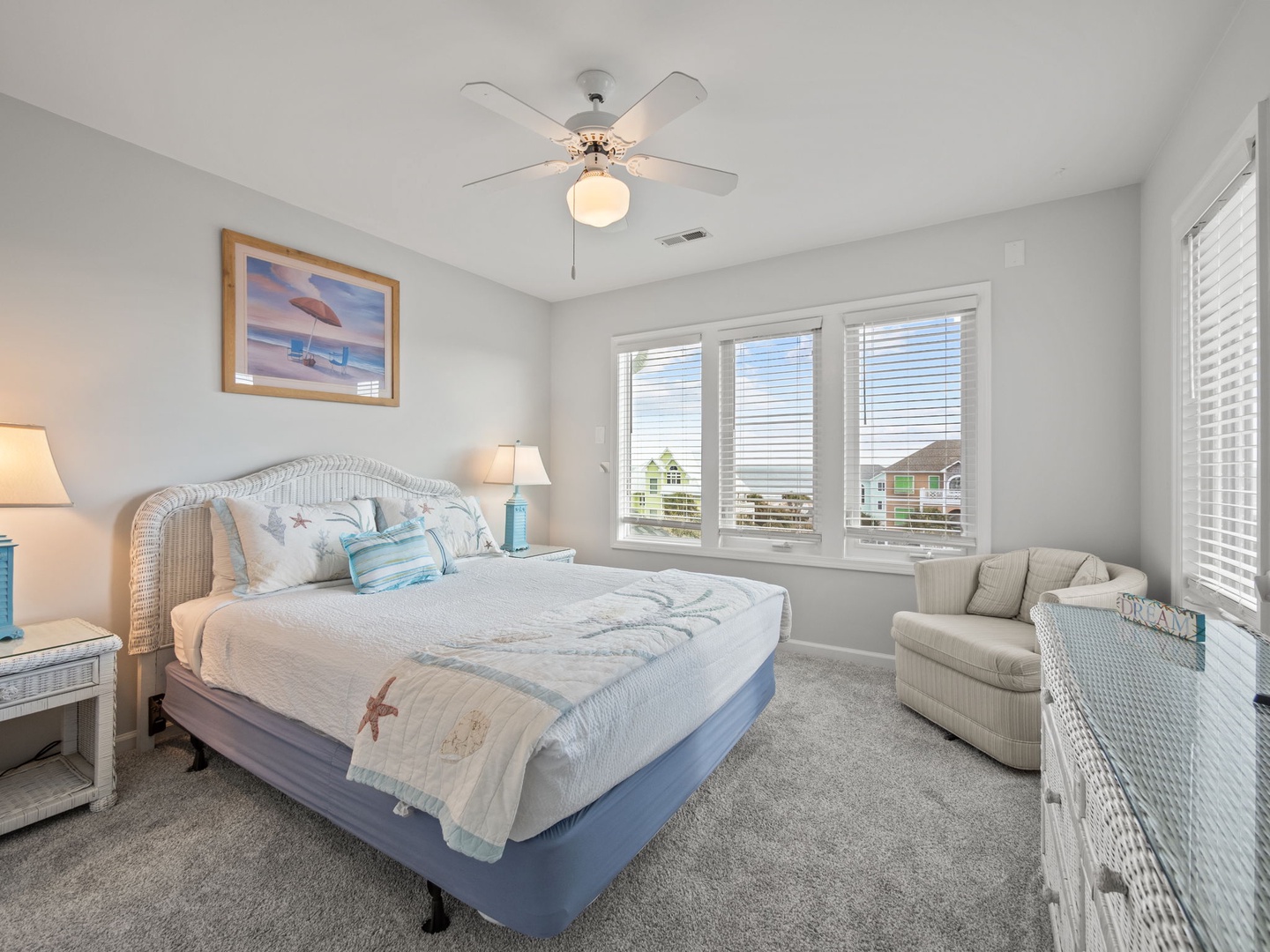 Drift off to sleep in your cozy coastal bedroom with ocean-themed decor and gentle ceiling fan breeze overhead.