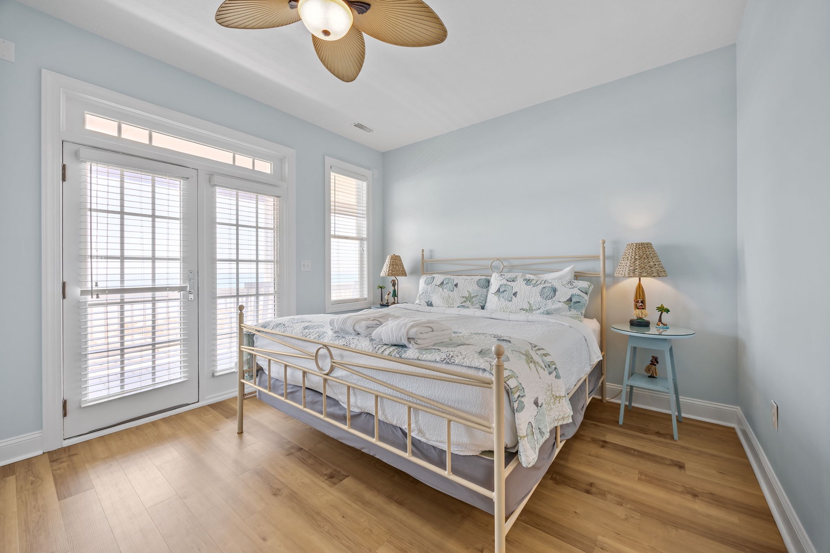Drift off to sleep in your serene coastal bedroom, where soft blue walls and warm wood floors create perfect tranquility.