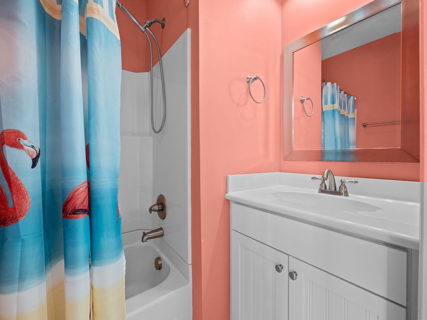 Refresh in your vibrant coral bathroom featuring a tropical flamingo shower curtain and modern amenities.