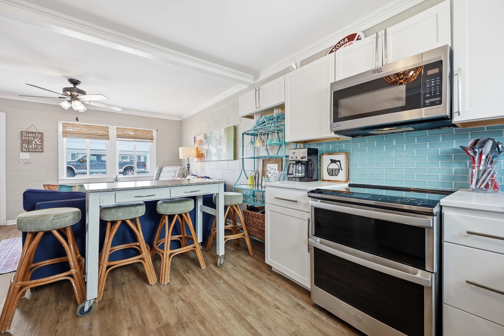 Picture yourself cooking in this bright coastal kitchen, complete with turquoise tile backsplash, stainless appliances, and a charming island where you can gather for meals and morning coffee together.
