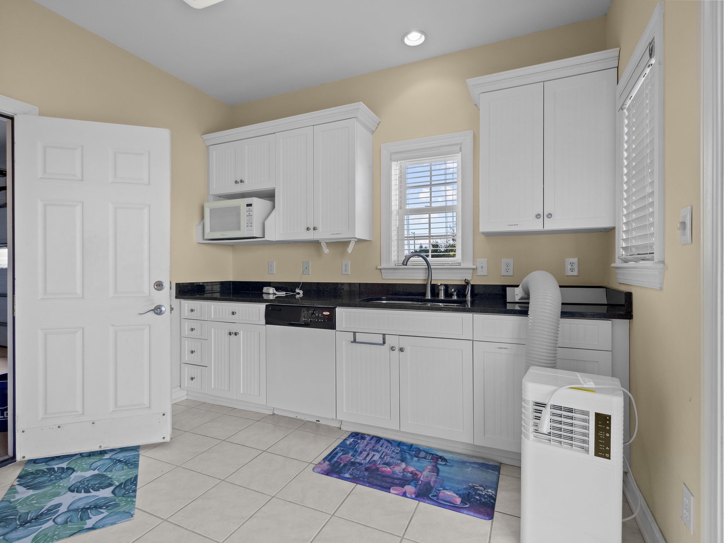 Step into your bright, fully-equipped kitchen featuring white cabinets, granite counters, and modern appliances for all your culinary adventures.