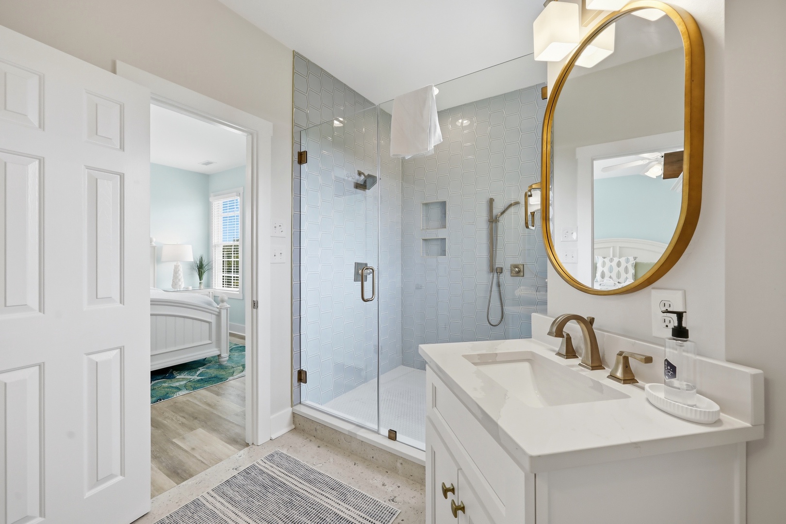 Unwind in your elegant bathroom with a spa-like rainfall shower, chic gold fixtures, and calming coastal hues that invite pure relaxation.