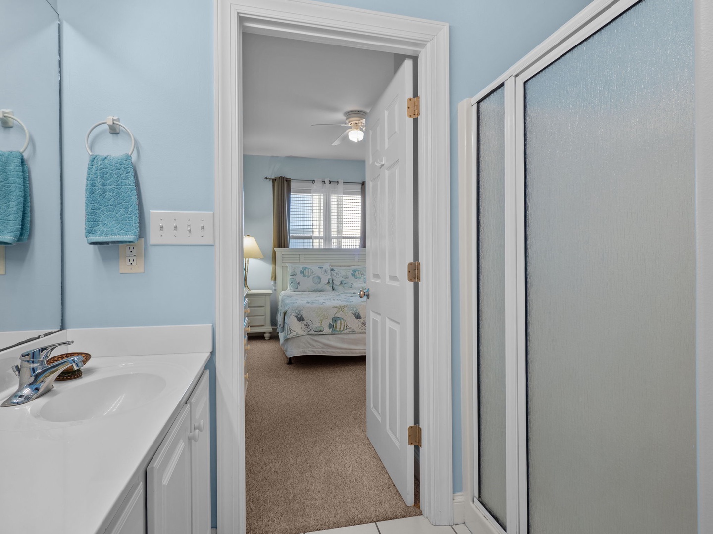 Step from your private bathroom into a peaceful bedroom retreat with soft coastal hues and comfortable bedding awaiting your arrival.