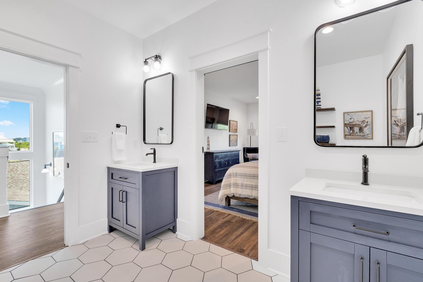Your stylish dual-vanity bathroom features modern fixtures and chic hexagonal tile flooring, with a view into the serene bedroom and easy access to your private outdoor space.