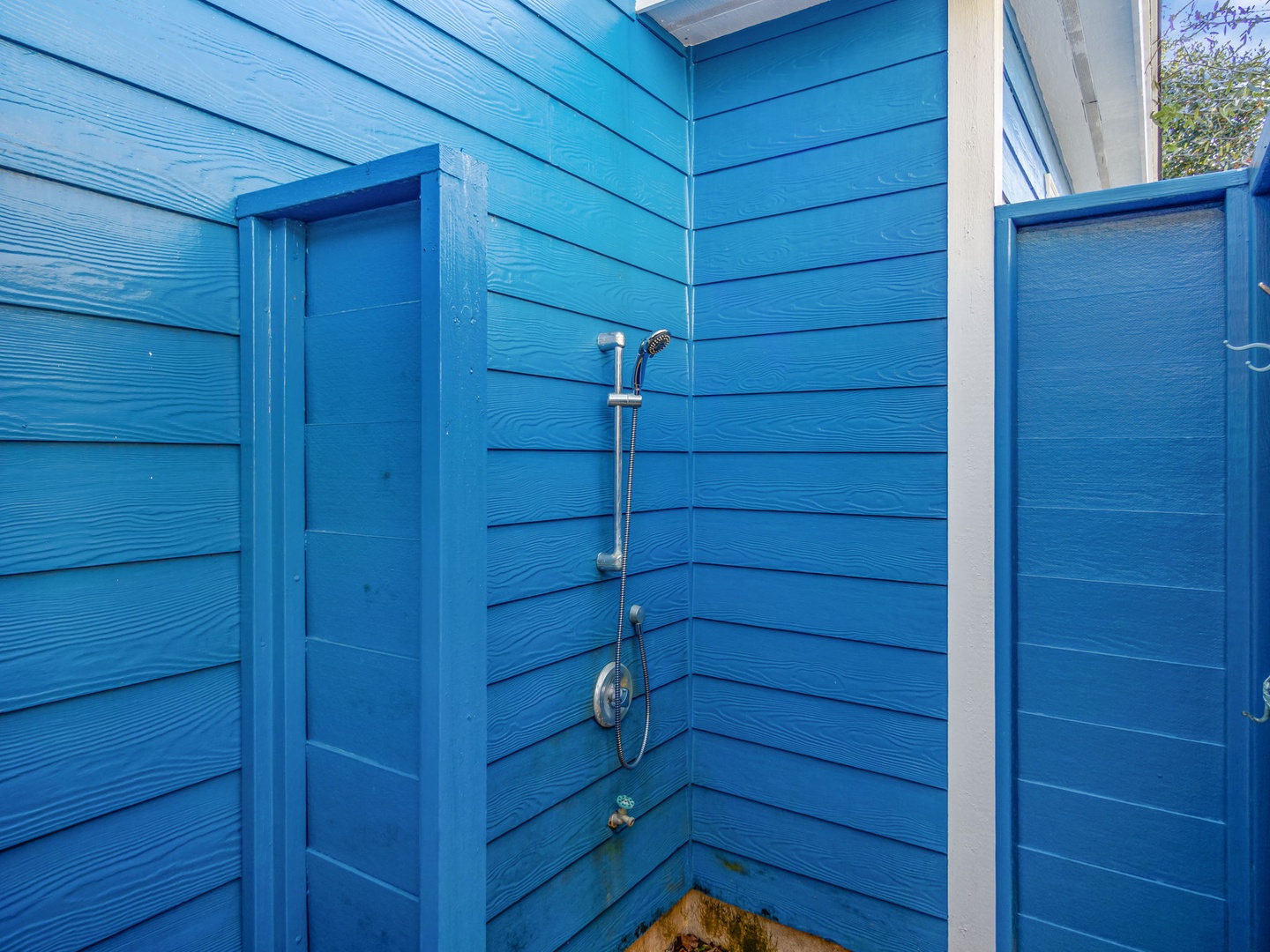 Rinse off after beach days in your private outdoor shower, surrounded by charming blue wood walls that create a refreshing coastal retreat.