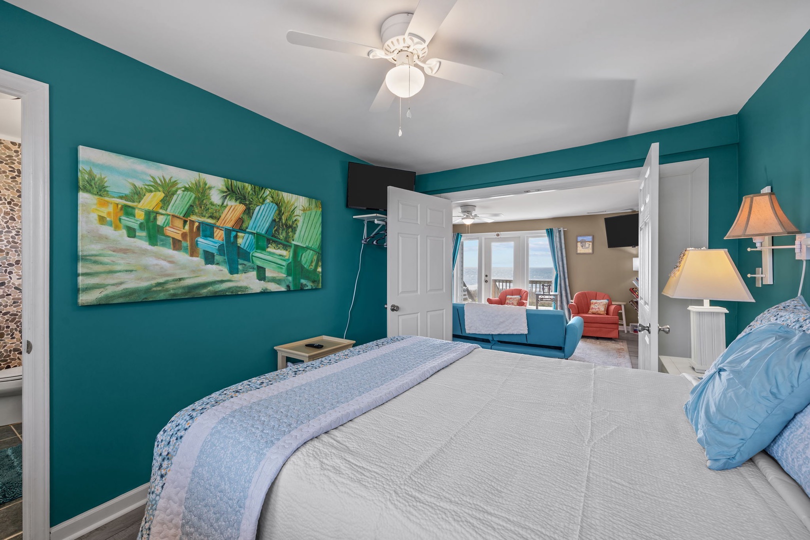 Your bright bedroom features vibrant turquoise walls and tropical artwork, with a ceiling fan keeping you cool and comfortable throughout your stay.