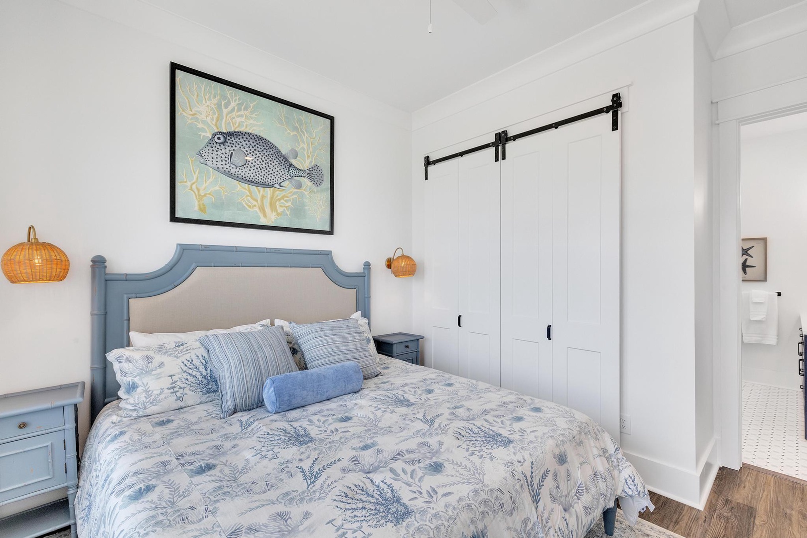 Drift off to sleep in this coastal-inspired bedroom featuring a charming barn door, soothing blue linens, and beachy décor that brings the ocean right to your doorstep.