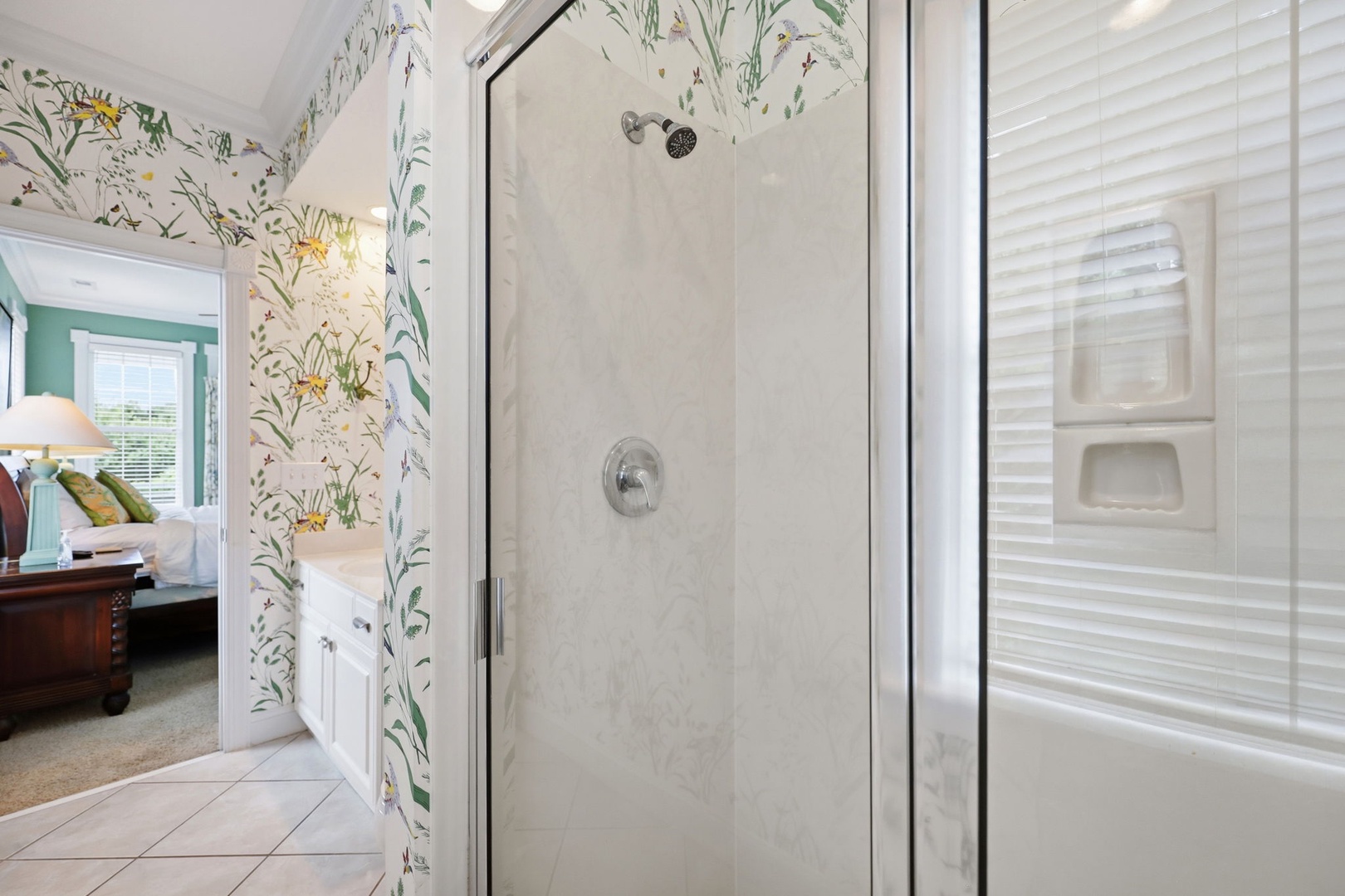 Step into your private bathroom, where botanical wallpaper brings nature indoors and a sleek glass-enclosed shower awaits your refreshing morning routine.