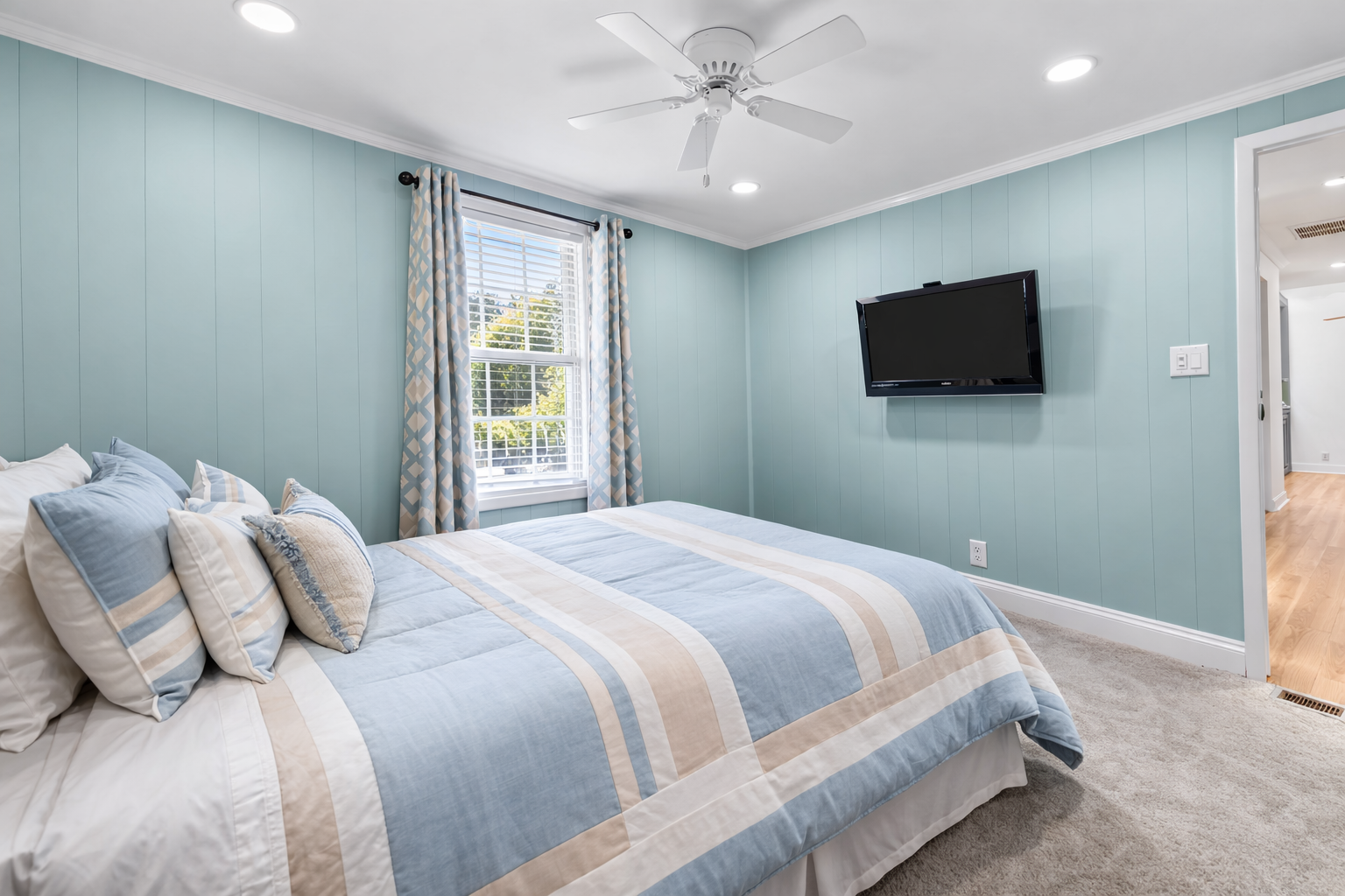 Drift off in this calming bedroom with soft blue hues, coastal bedding, and wall-mounted TV for your evening entertainment.